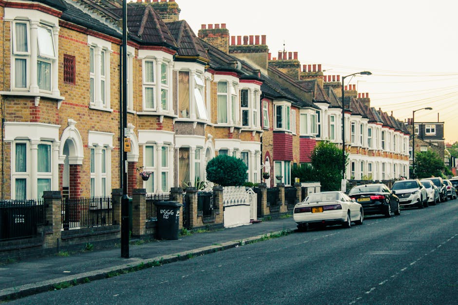 Photograph of a row of terraced houses on Prince of Wales Drive in Battersea, showing front yards with low brick walls and decorative fencing, with some houses having bay windows and brick facades. Se